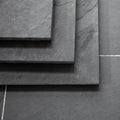 Stacked Brazilian black riven slate hearth slabs showing surface texture