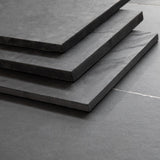 Stacked Brazilian black riven slate hearth slabs showing the sawn edge finish