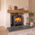 Riven black slate fireplace hearth slab installed under log burner with oak mantle