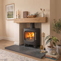 Low-profile graphite black slate hearth stone slab providing floor protection for an indoor wood-burning stove.